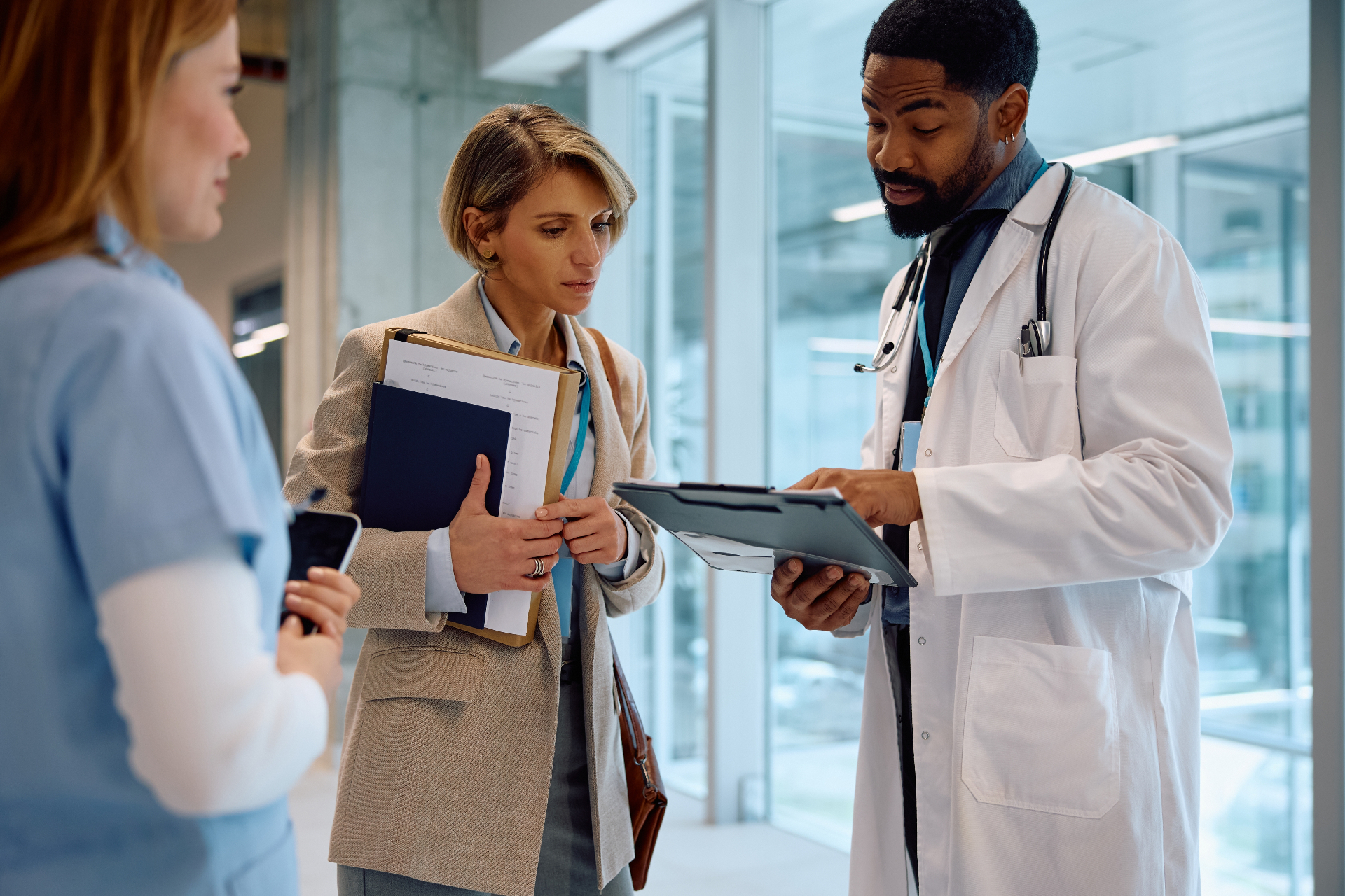 Medical professionals collaborating and reviewing patient information in a clinic hallway